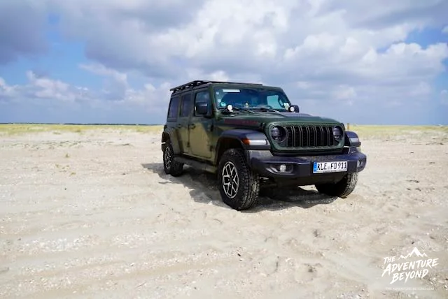 Jeep Wrangler auf dem weiten Strand von Rømø unter einem dramatischen Wolkenhimmel