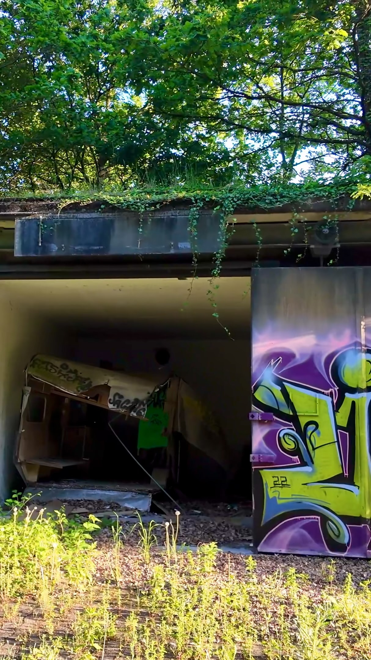 Offener Bunker mit Graffiti am Tor und zurückgelassenem Material im Inneren