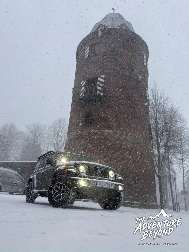 Jeep vor einem Backsteinturm im dichten Schneefall