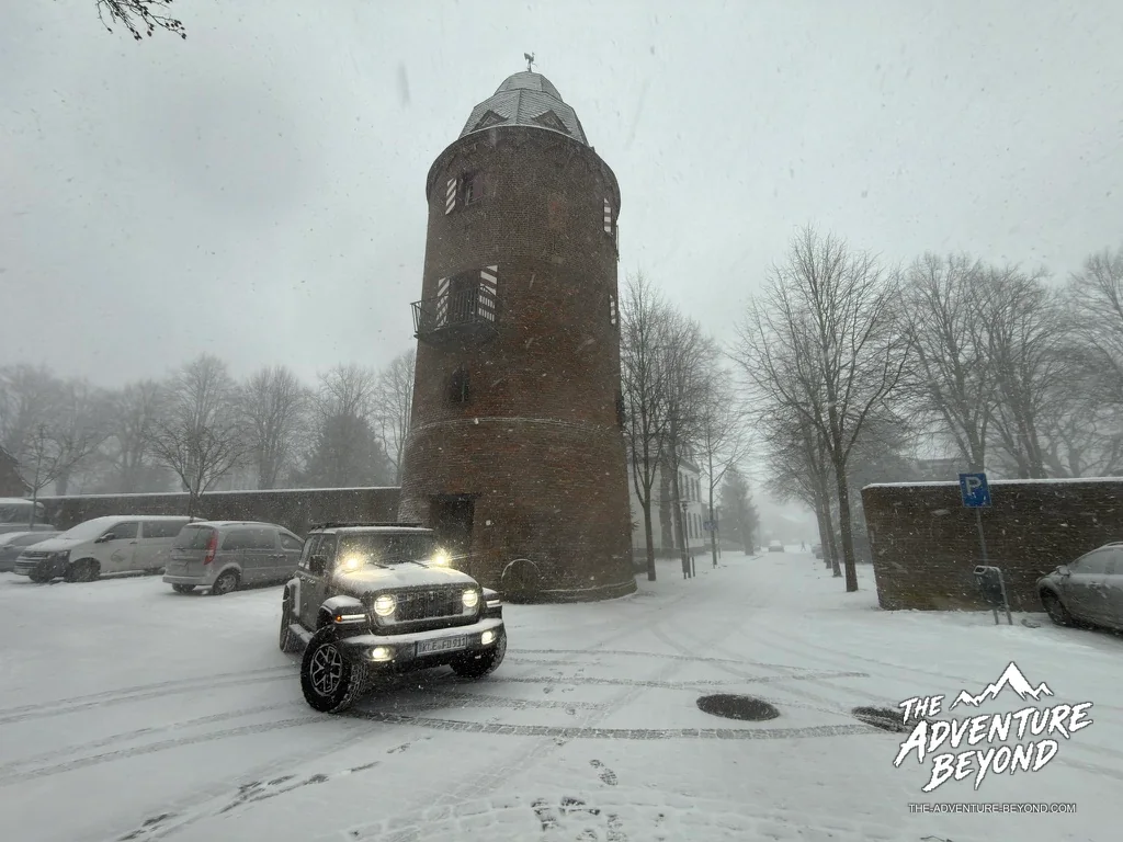 Verschneiter Platz mit Backsteinturm und Jeep