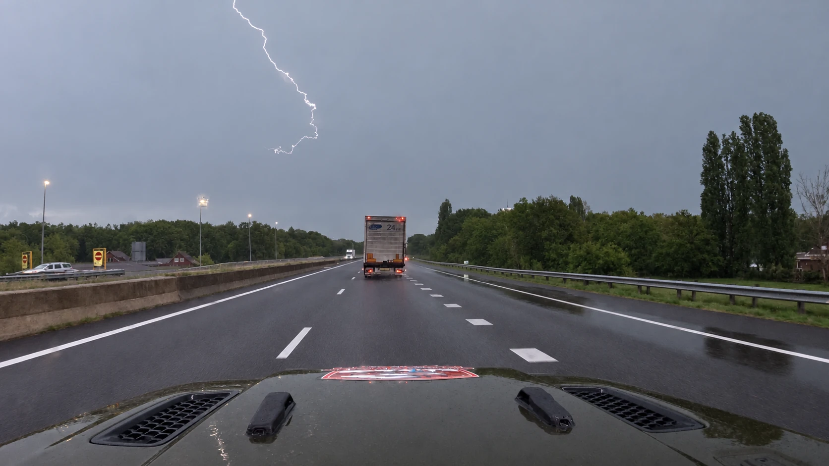 Heller Blitzkanal über der Autobahn, gesehen über die Motorhaube des Jeeps