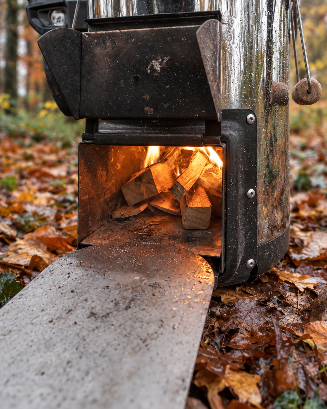 De brandstoftoevoer aan de zijkant met open klep: hier kan ik hout bijvullen en het vuur in de gaten houden.