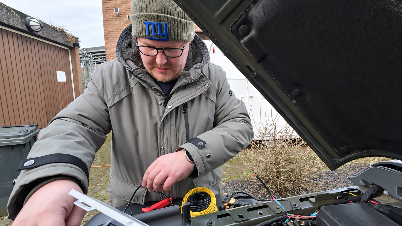 Florian arbeitet bei geöffneter Motorhaube an der Verkabelung.