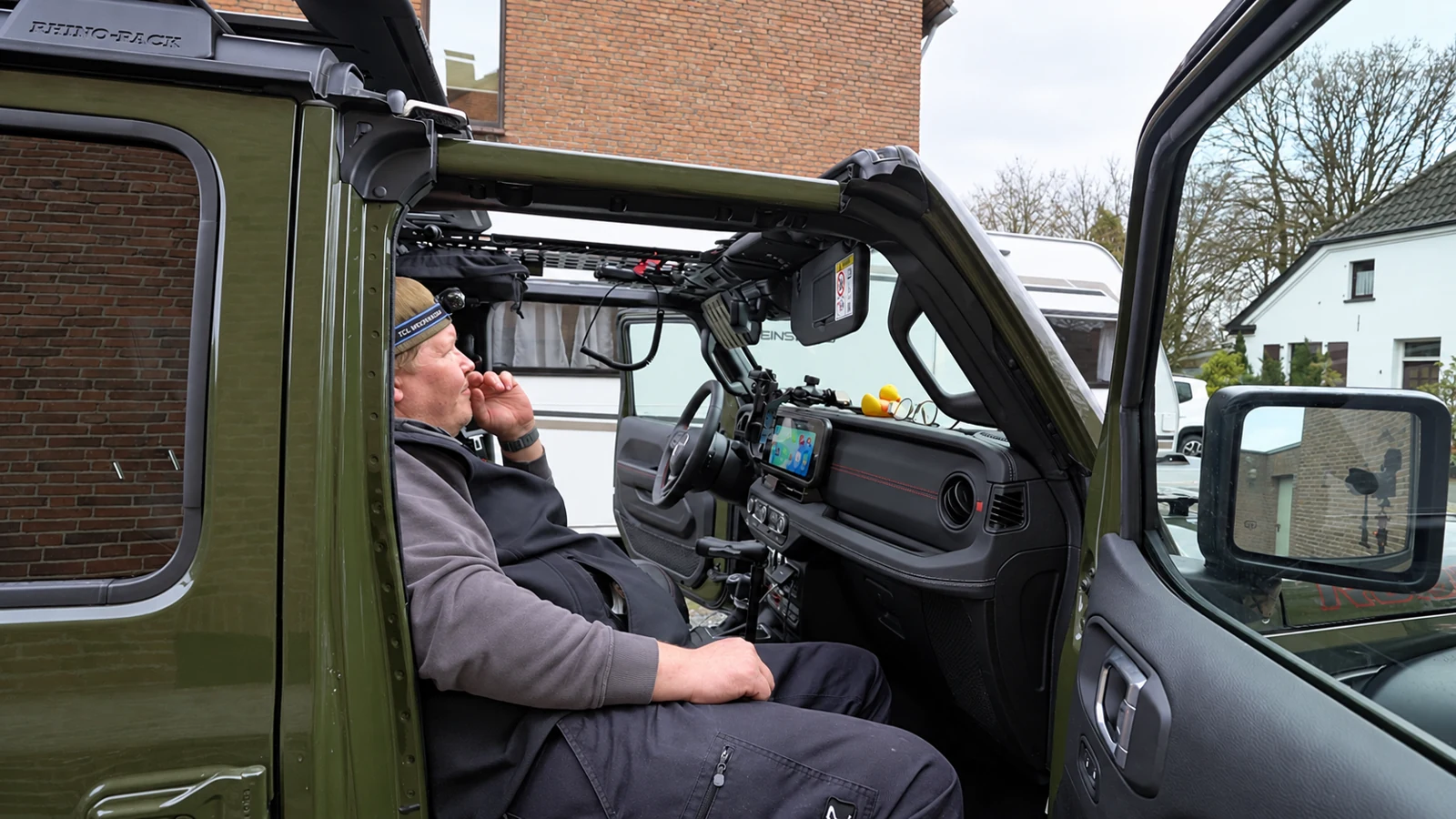 Florian im Cockpit seines Jeep Wrangler während des CB-Funk-Einbaus, durch die offene Beifahrertür fotografiert.