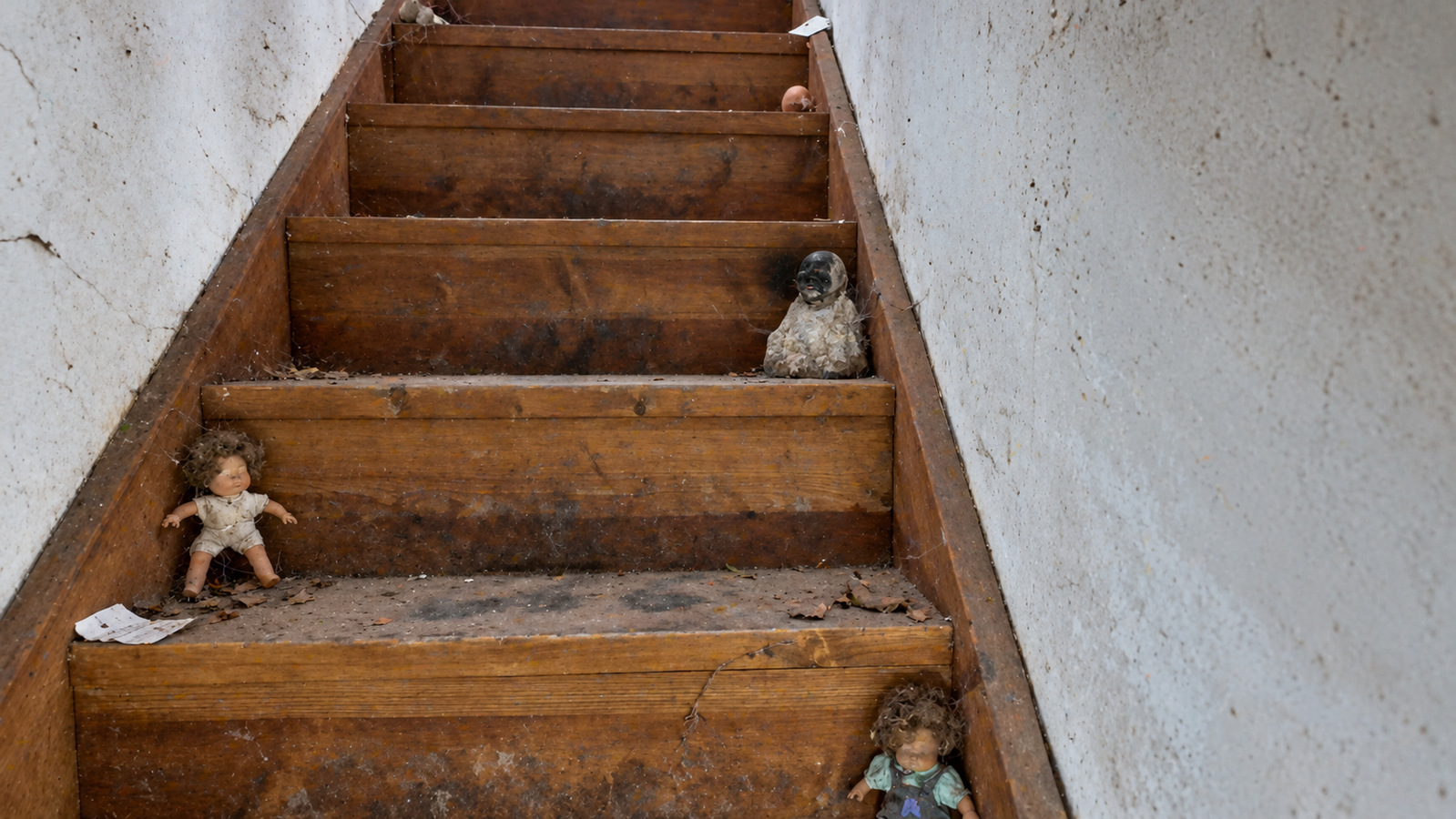 Kleine poppen op de versleten houten trap in de verlaten boerderij