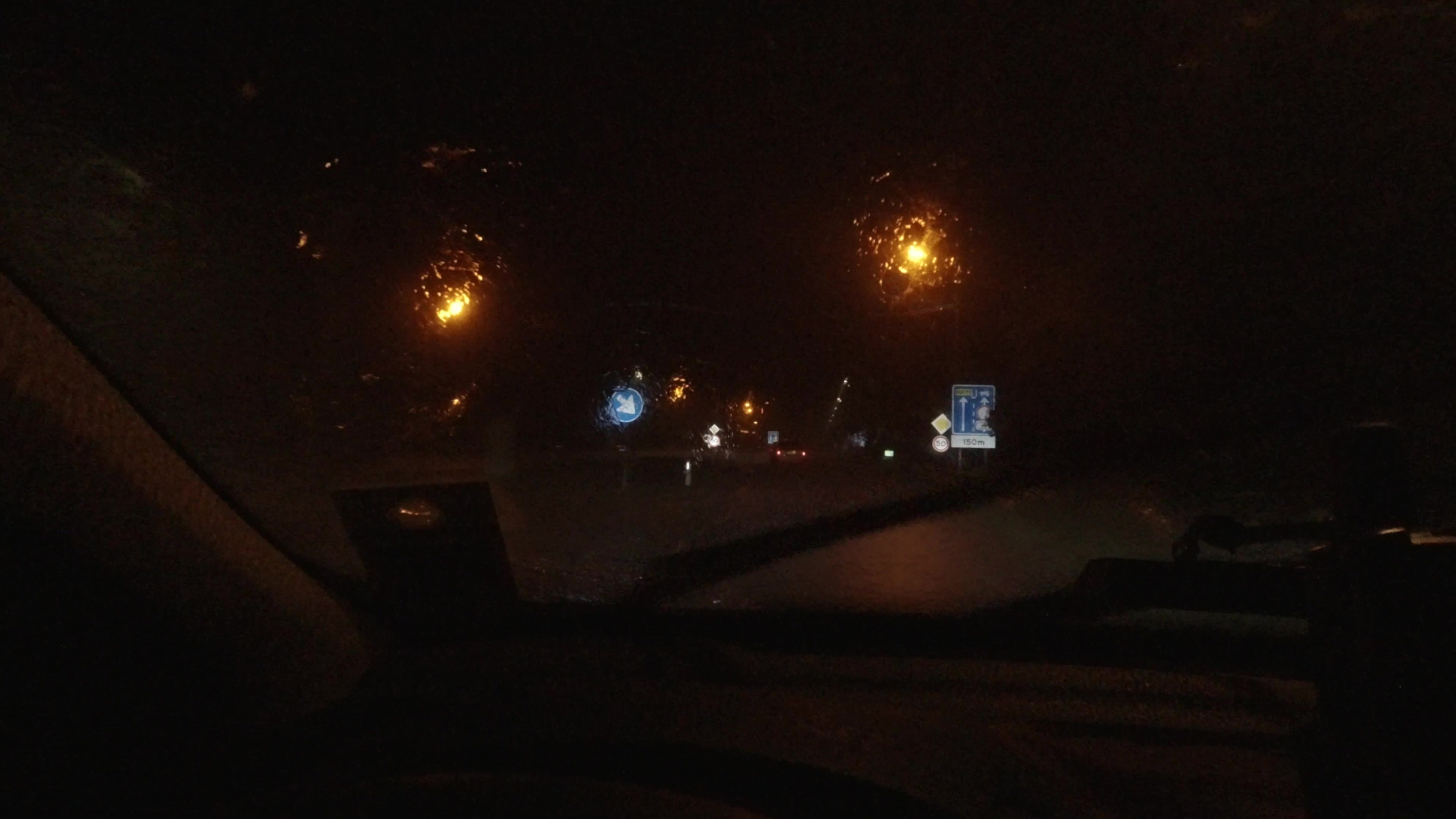 Straatlampen door de natte voorruit.