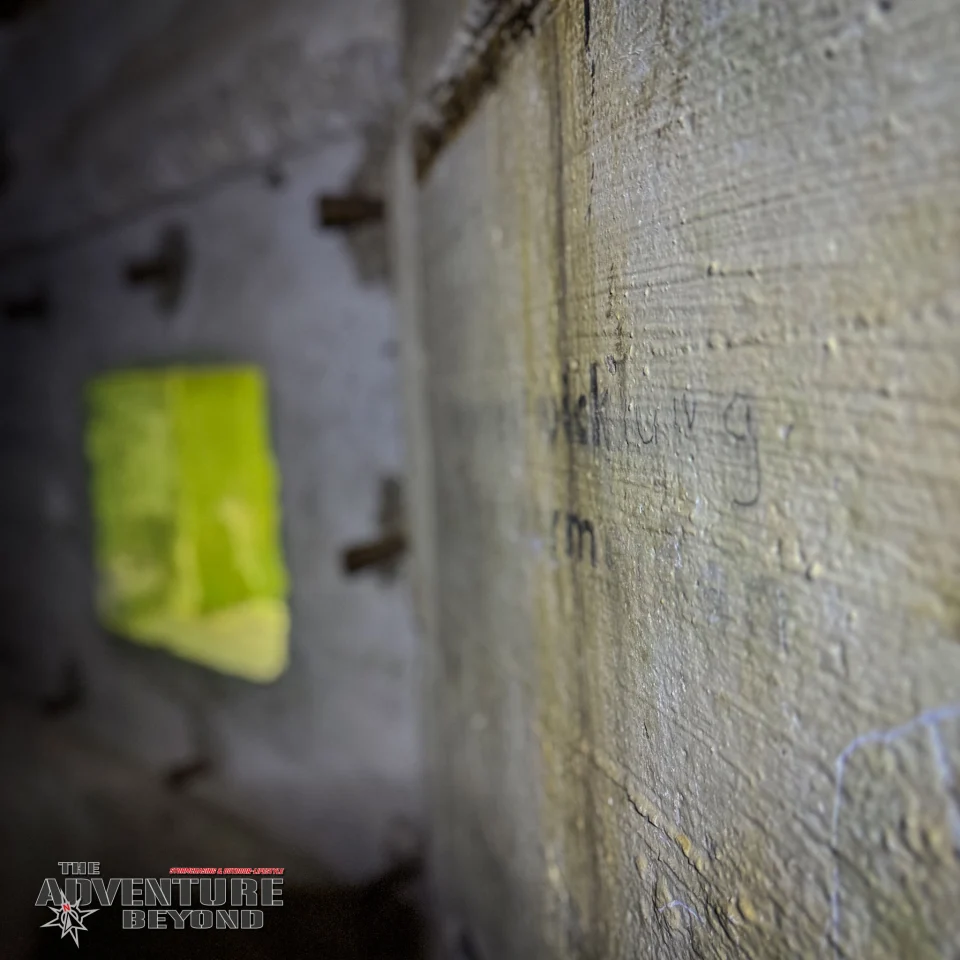 Verblasste Schrift und eine Öffnung in der Bunkerwand.